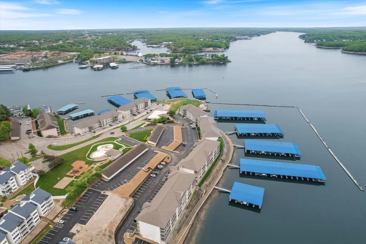 A vibrant marina scene featuring a waterfront lined with boats docked along the shoreline, lush landscape in the background, and calm blue water reflecting the sky. The area is bustling with opportunities for boating, fishing, water sports, and picnicking, embodying the spirit of lakeside adventure.
