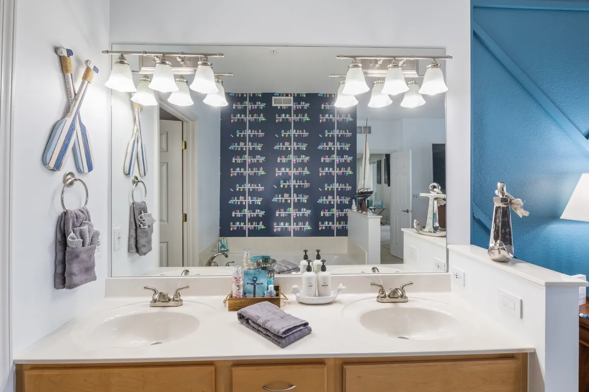 A bright bathroom with double sinks, a stylish nautical-themed wall, and a well-lit mirror. The design is fresh and functional, enhancing the sense of a well-equipped, relaxing space for daily routines.