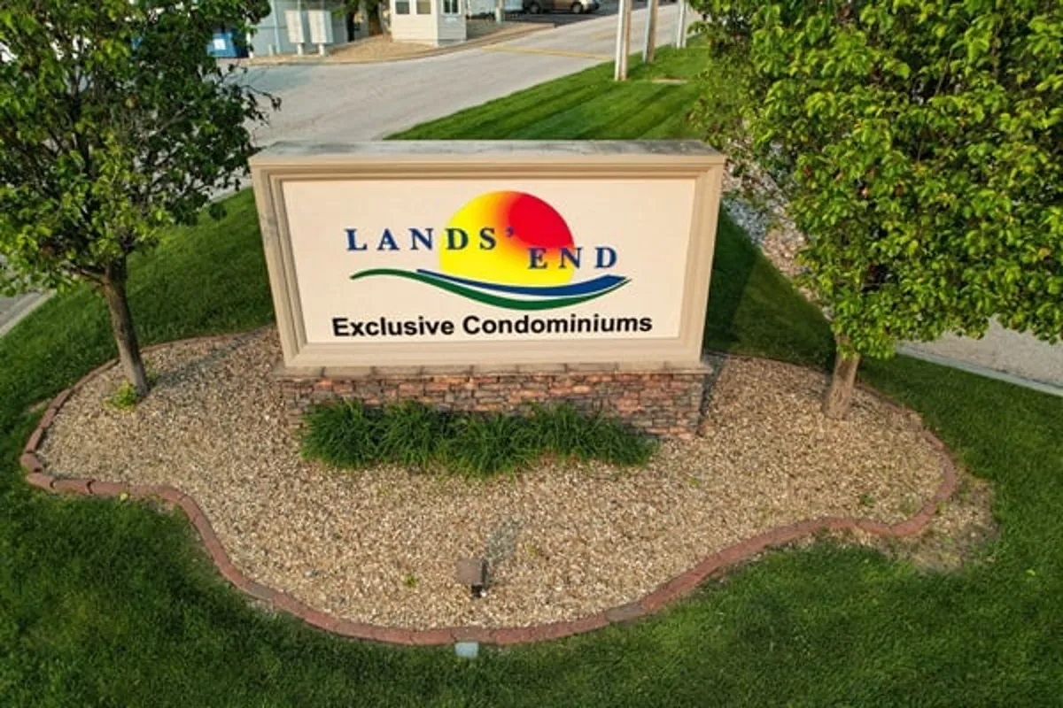 A welcoming exterior scene with clear signage, manicured landscaping, and a winding pathway leading into a central community area. Soft evening light suggests a sense of arrival, sociability, and the promise of local connections and relaxing outdoor moments.