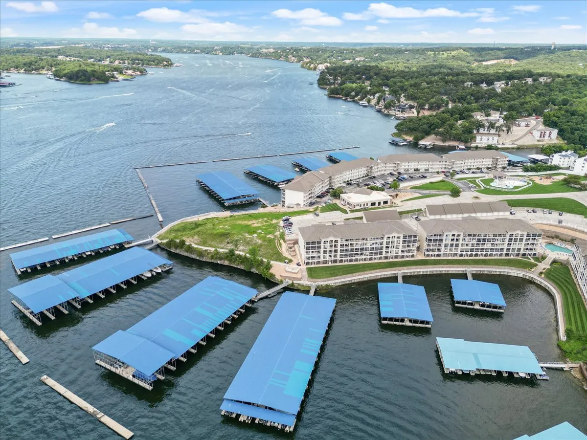 A vibrant waterfront scene features marina docks, luxury apartments, and lush greenery. The docks are busy with boats, and the peaceful water invites a sense of adventure. The backdrop of modern waterfront properties highlights the area's appeal for water enthusiasts and easy marina access.