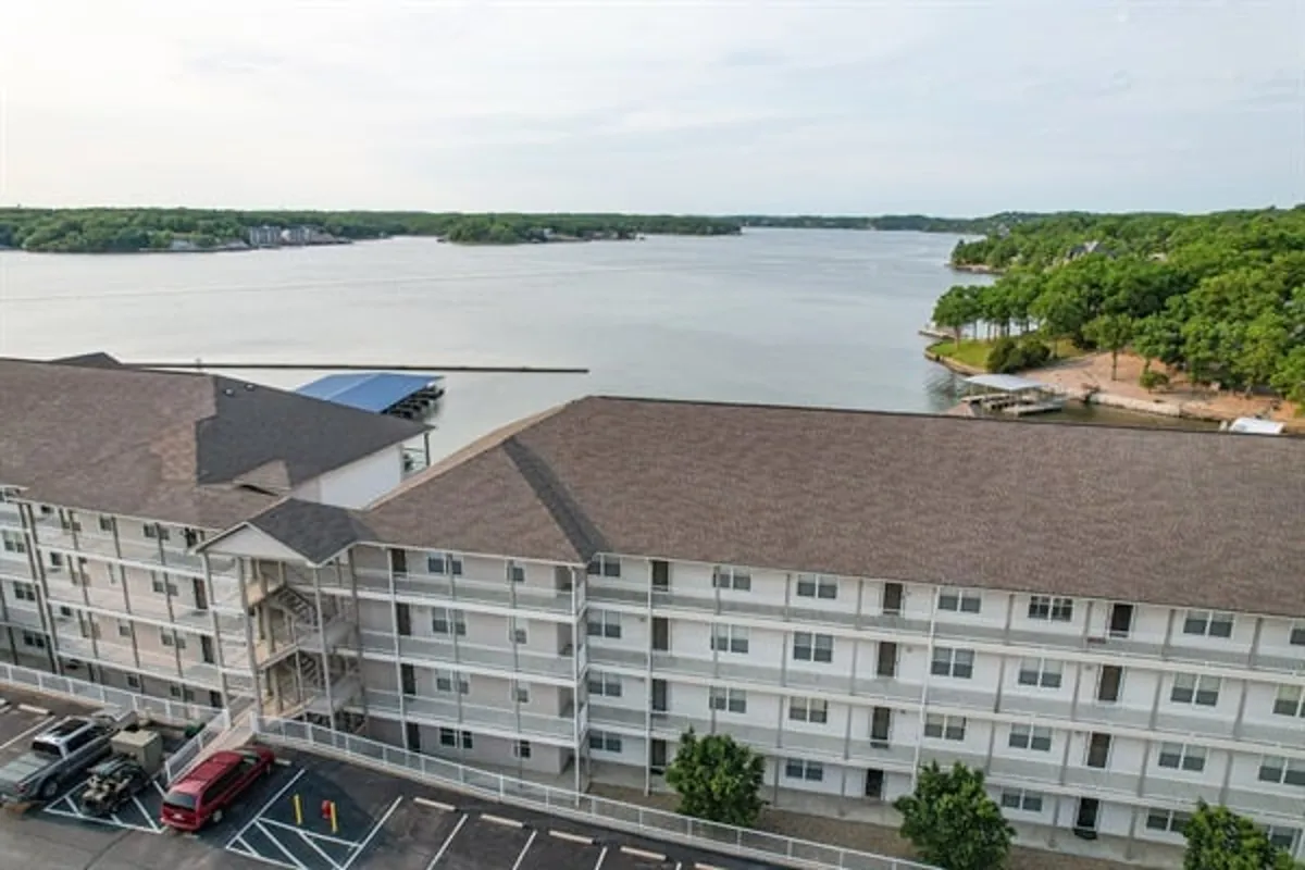 A tranquil lake view with lush greenery surrounds the waterfront, with the building structure visible in the background. The stillness of the water and the natural landscape create a peaceful, romantic atmosphere perfect for quiet reflection or gentle exploration.